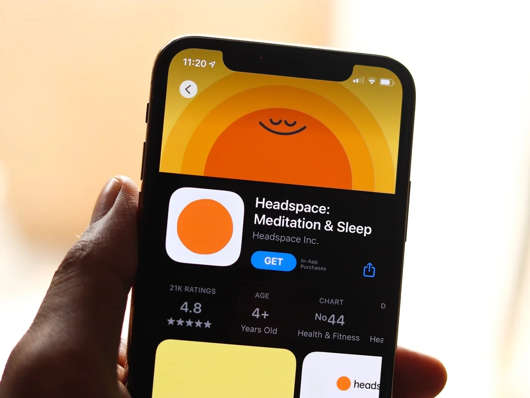 A person sitting peacefully in a serene setting, practicing meditation with the Headspace app on their smartphone nearby.